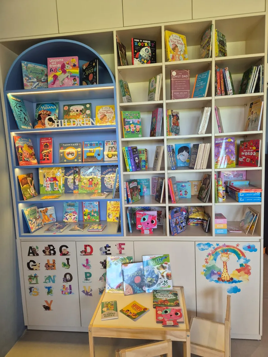 Nouvelle's children's corner: a blue arched bookcase labelled Children, cream cubby shelves of picture books, alphabet stickers on the cupboards and a small table with two child-size chairs